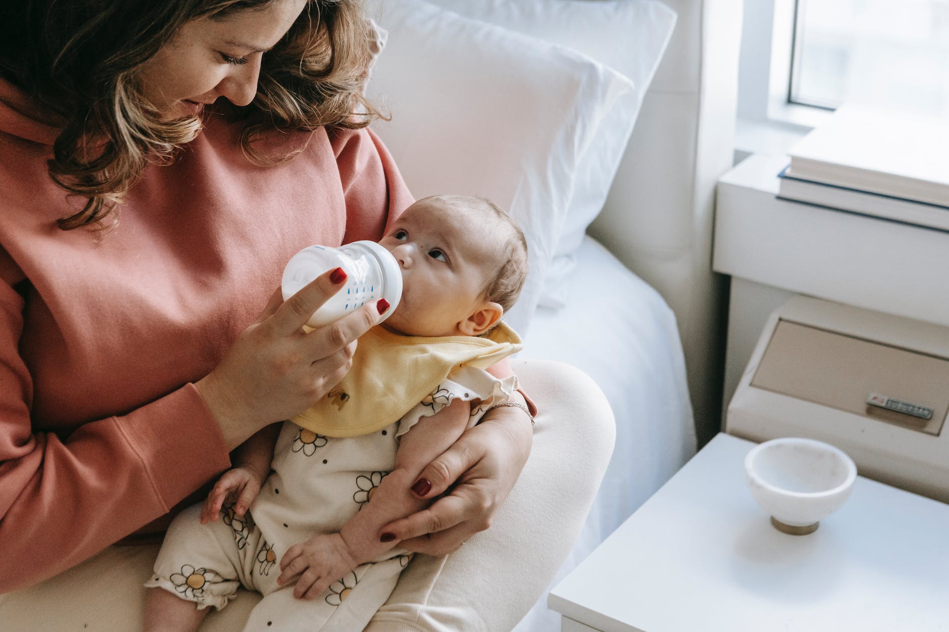 smiling young mother feeding baby with milk from bottle