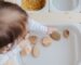 crop anonymous child getting brown stones from white container at home