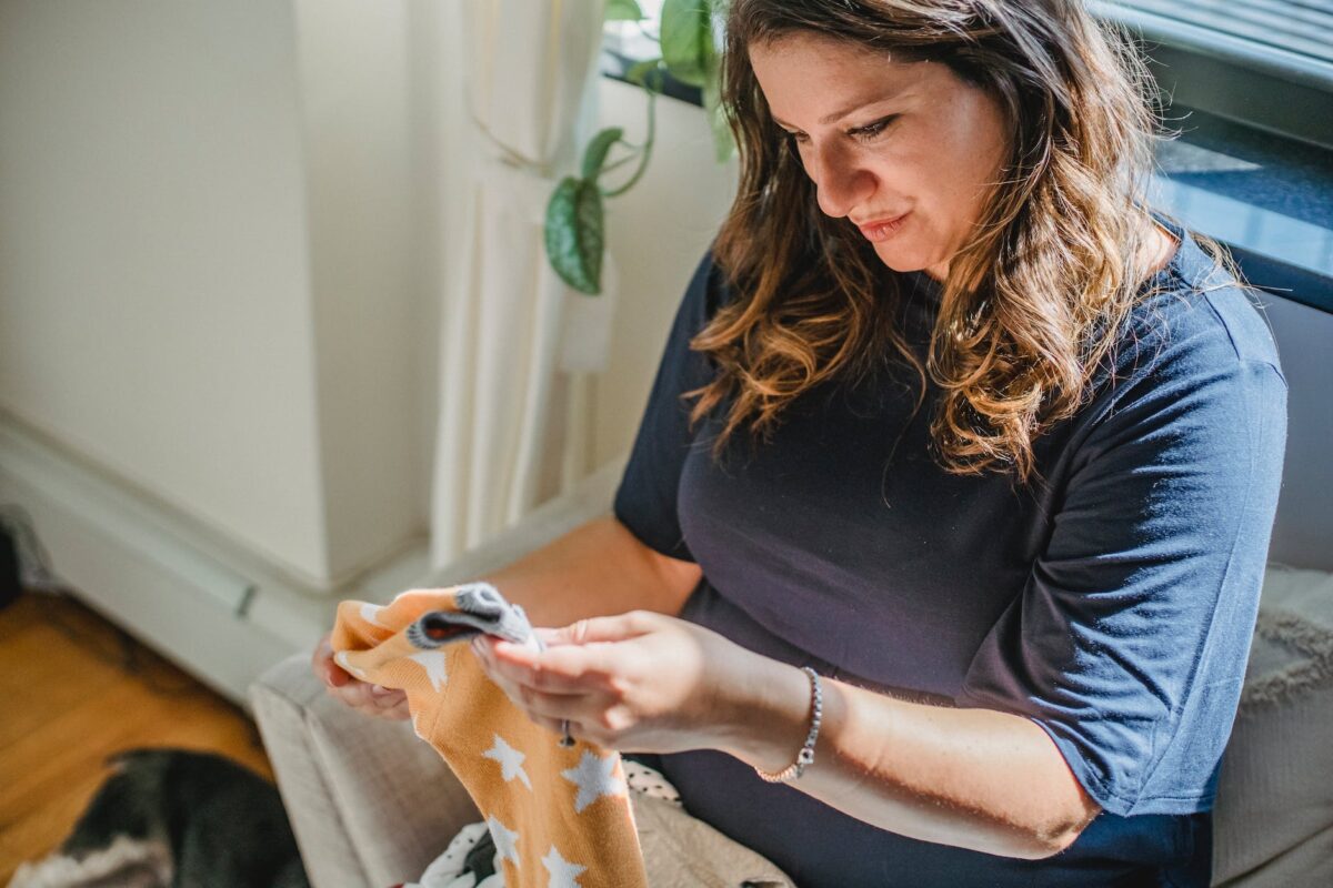 happy pregnant woman preparing new cloth for coming child